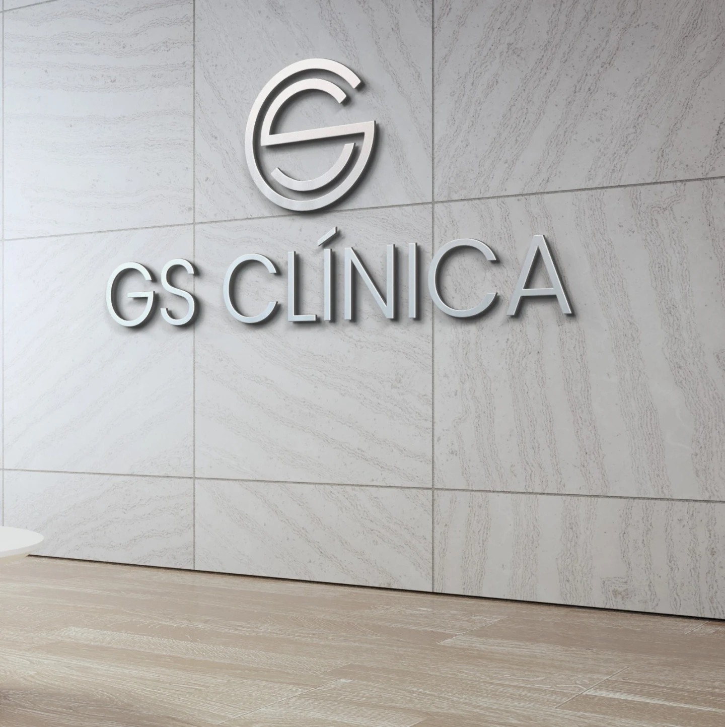 Logotipo em relevo prateado para a GS Clínica aplicado em parede decorativa cinza com textura de mármore