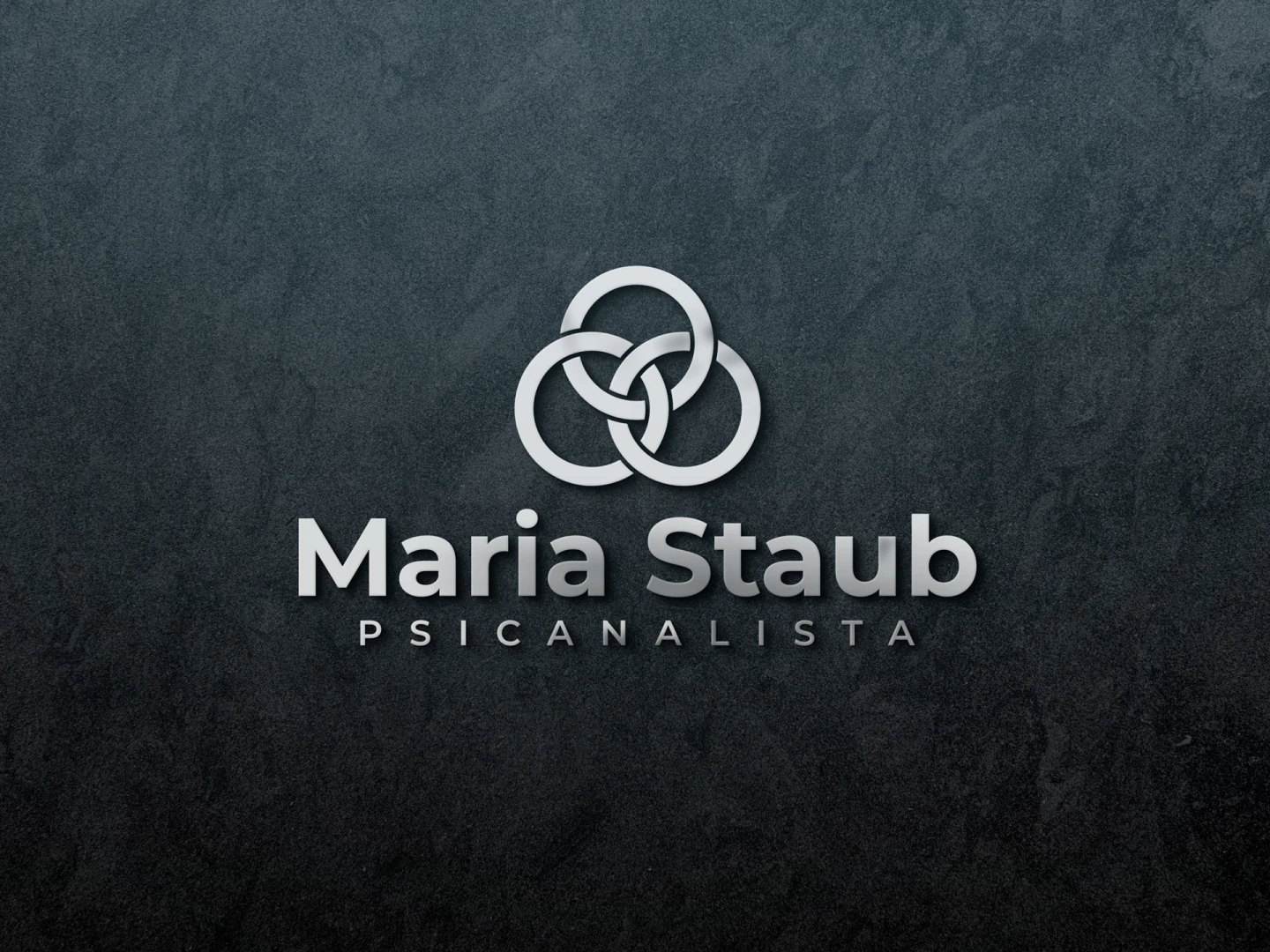 Logotipo em relevo prateado com anéis entrelaçados para a psicanalista Maria Staub sobre fundo escuro.