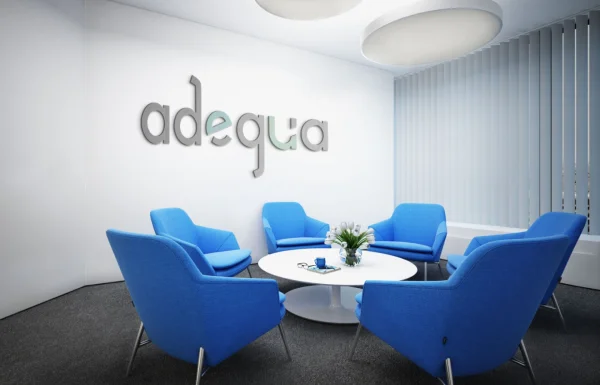 Logotipo moderno da empresa Adequa aplicado em parede de recepção corporativa com poltronas azuis, representando o serviço de criação de logo para serviços gerais.