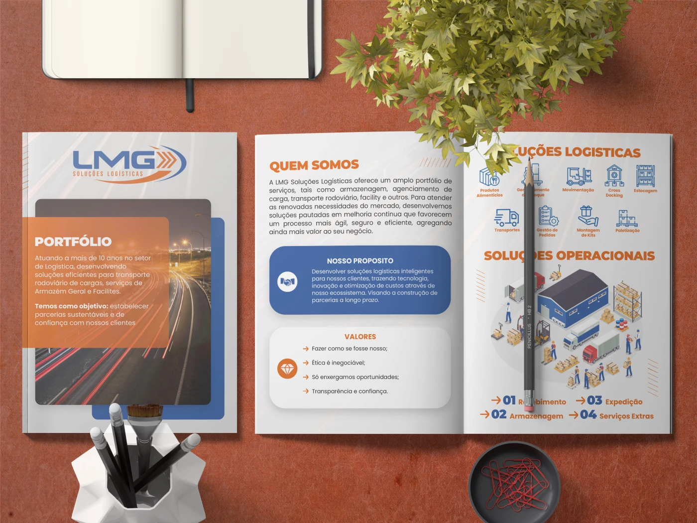 Mockup de portfólio empresarial da LMG Logística aberto sobre uma mesa, exibindo páginas com design azul e laranja e fluxogramas operacionais.