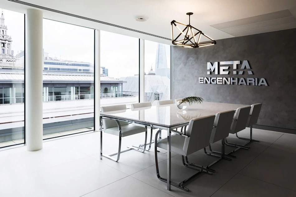 Logotipo da Meta Engenharia aplicado em parede de cimento queimado em sala de reuniões moderna.